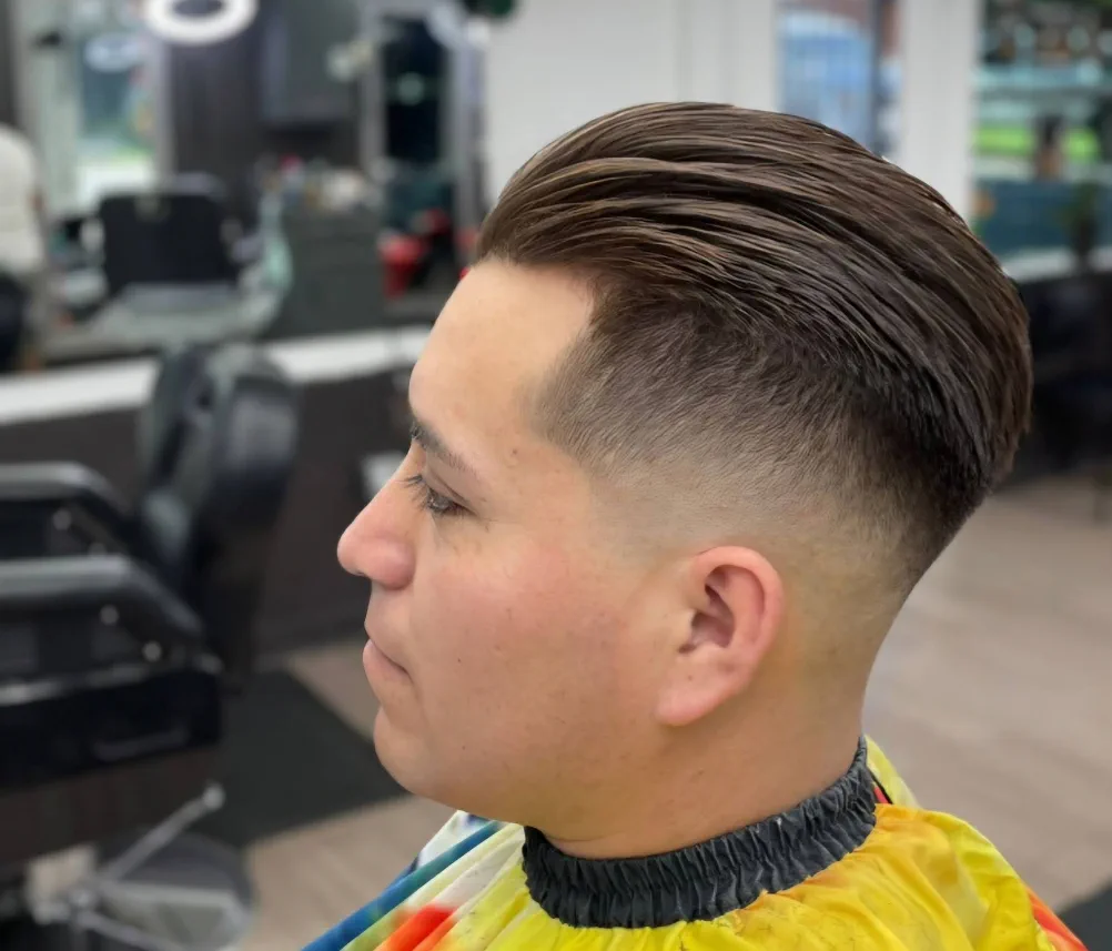 Men's slicked-back taper fade in profile.